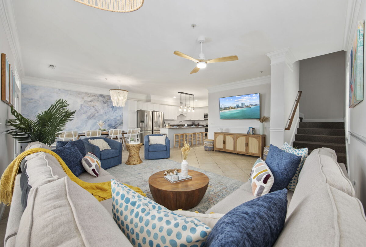 Open-plan living room and kitchen with blue sofas and a round wood table