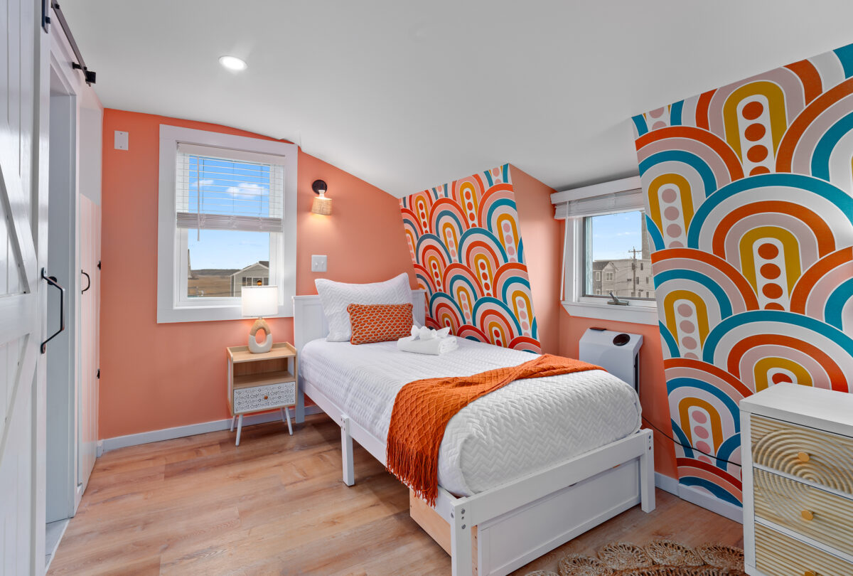 Attic bedroom with a rainbow arch mural and a coral accent wall