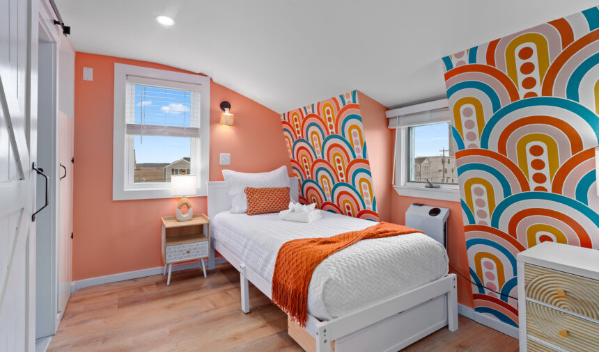 Attic bedroom with a rainbow arch mural and a coral accent wall