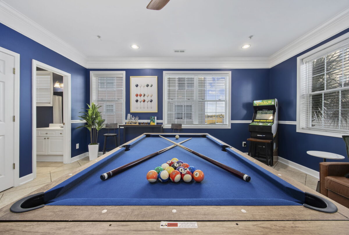 Games room with a blue pool table, arcade cabinet and navy walls