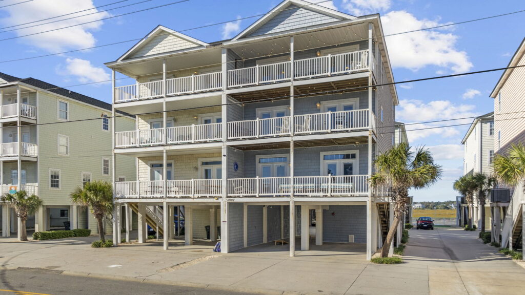 Three-storey grey beach house with white balcony railings