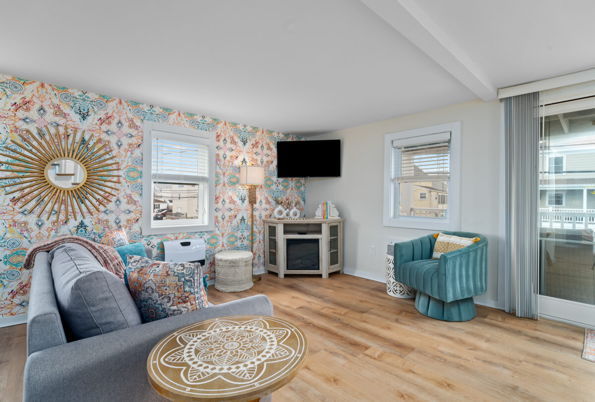 Living room with floral wallpaper, a teal armchair and a round rug