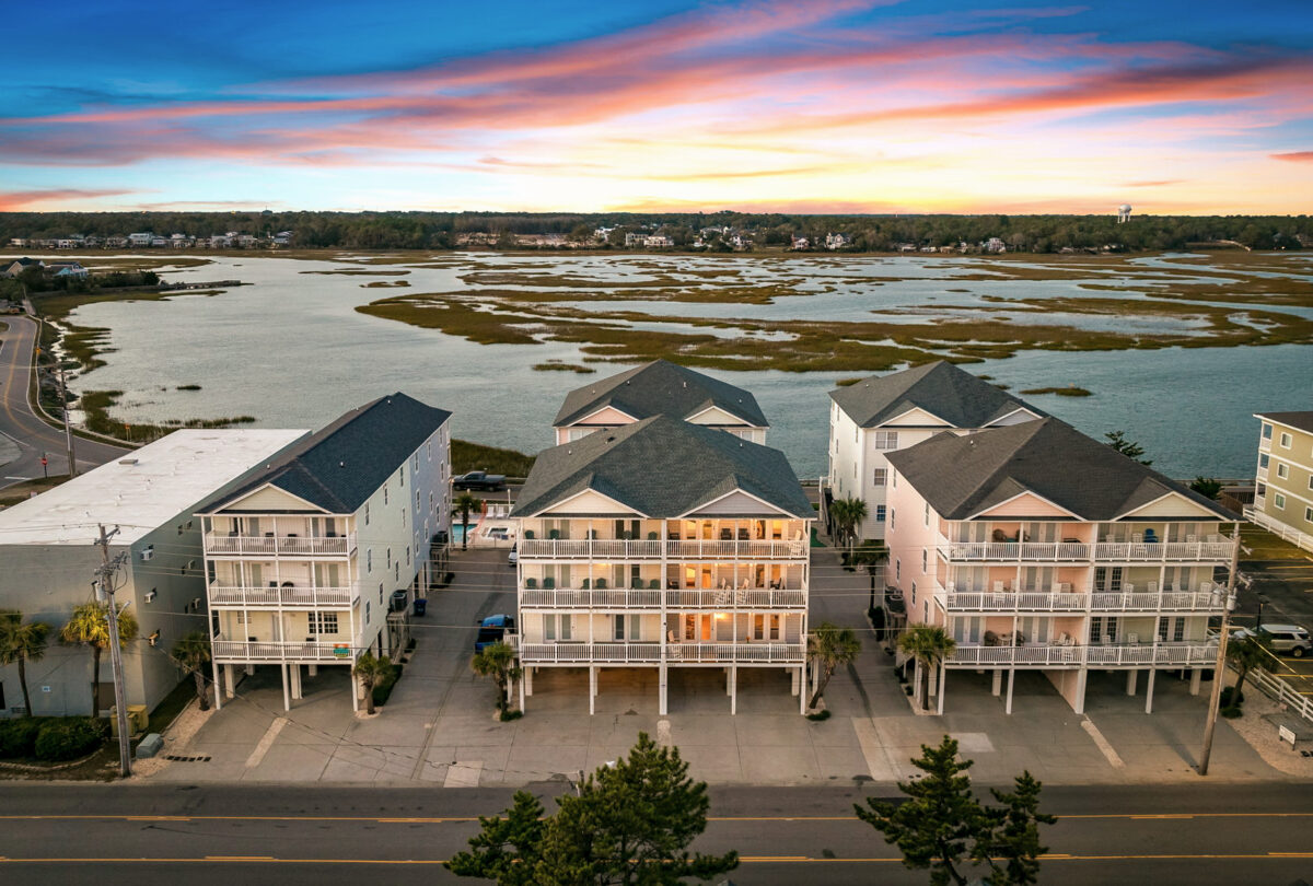 Aerial view of beach houses at sunset beside a tidal marsh
