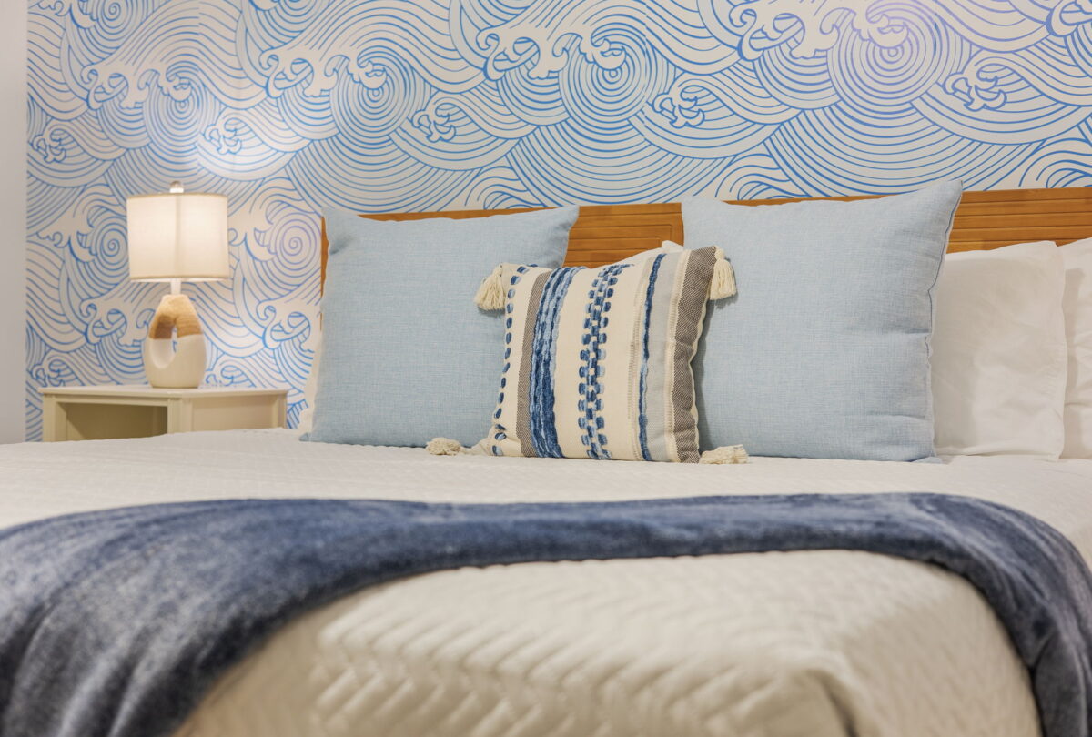 Bed with striped cushions against a blue wave mural
