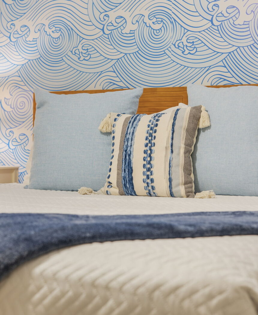 Bed with striped cushions against a blue wave mural