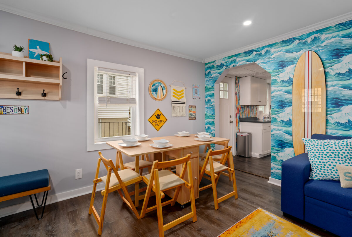 Dining area with wooden chairs beside an ocean-wave feature wall