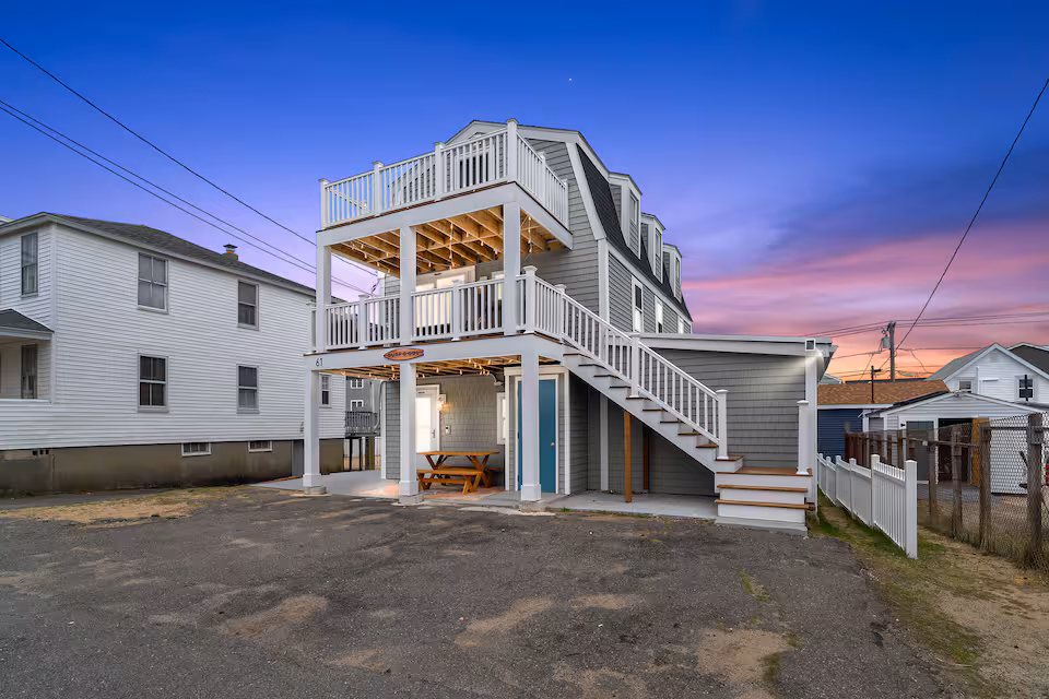 Three-storey beach house at dusk with white staircases