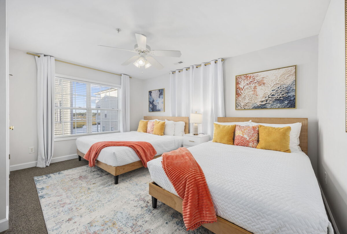 Bedroom with two beds, coral throws and woven headboards
