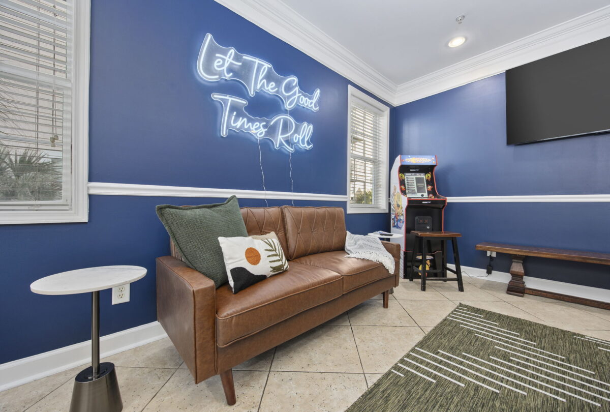 Lounge with a leather sofa, navy walls and a neon Let The Good Times Roll sign