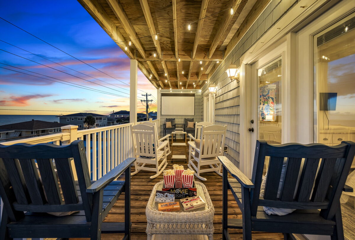 Covered porch at dusk with rocking chairs and a projector screen