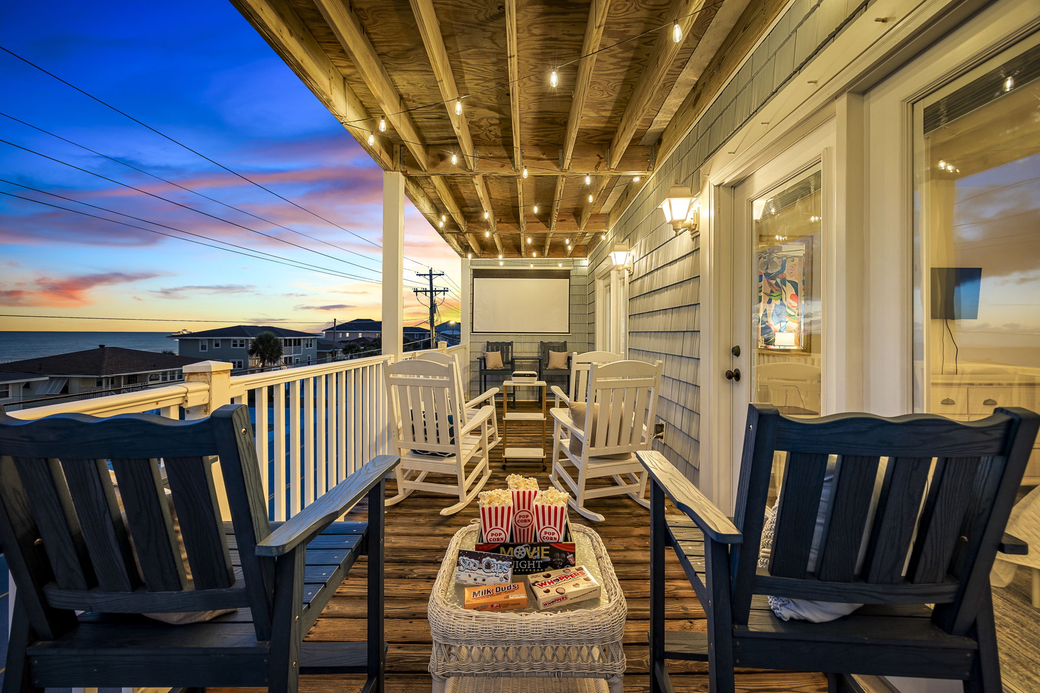 Covered porch at dusk with rocking chairs and a projector screen