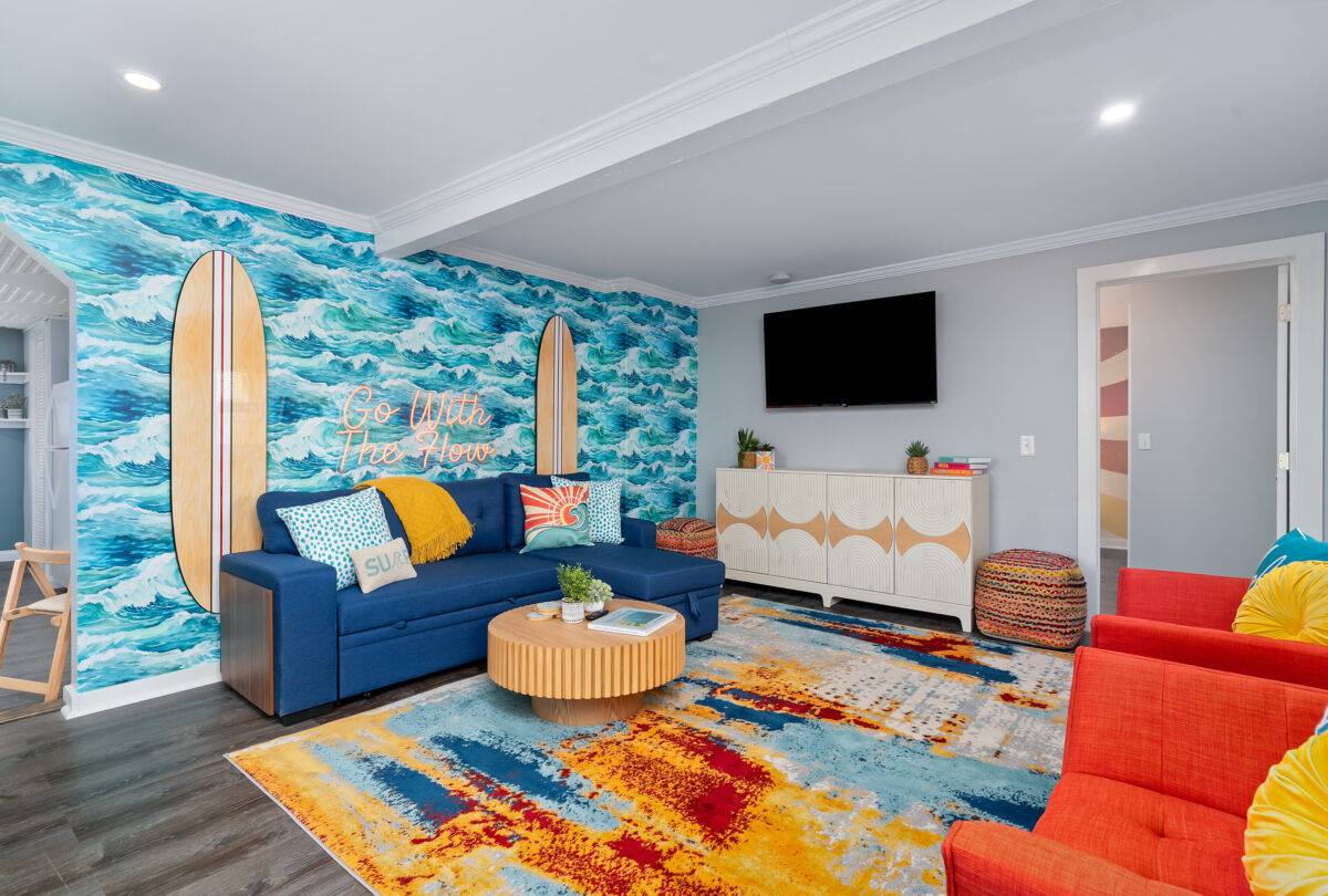 Lounge with an ocean mural, blue sofa and a bright abstract rug
