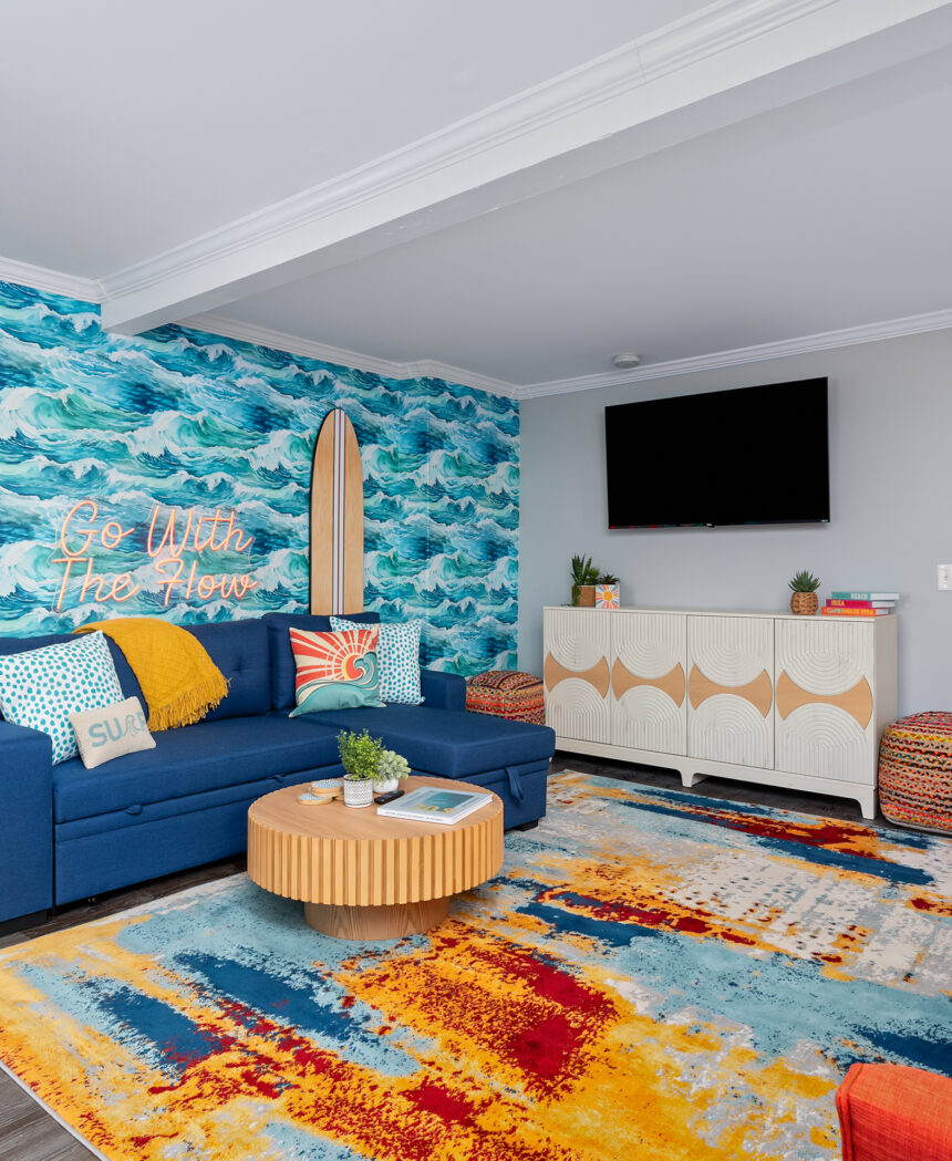 Lounge with an ocean mural, blue sofa and a bright abstract rug