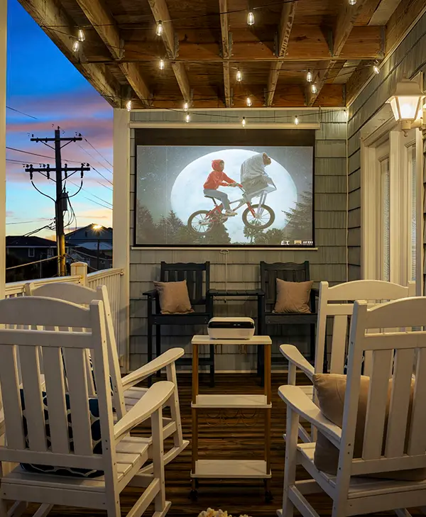 Covered porch with a projector screen showing a film at dusk