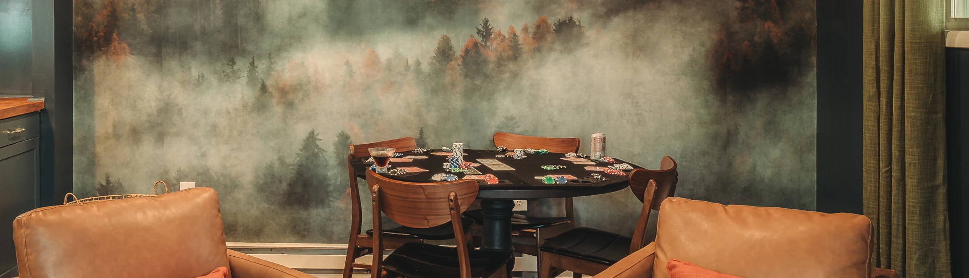 Poker table set with chips in front of a misty forest mural