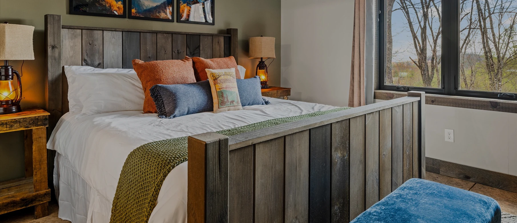 Bed with layered rust and blue cushions behind a reclaimed timber headboard