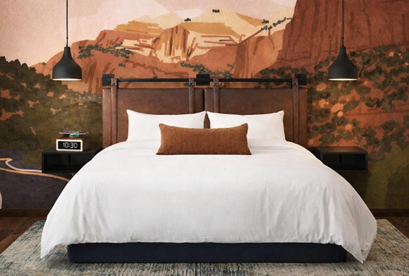 Hotel bed beneath a canyon landscape mural