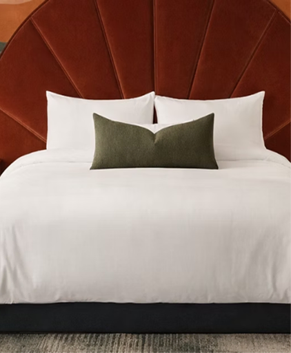 Hotel bed with a fluted rust velvet headboard and a green cushion