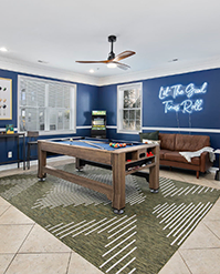 Games room with a shuffleboard table and a neon sign on a navy wall