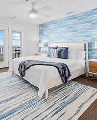 Bedroom with a coastal mural and a navy throw on a white bed