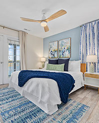 Bedroom with a navy throw, bird prints and a balcony door