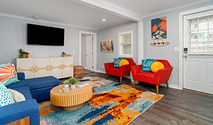 Living room with red armchairs and a bright abstract rug