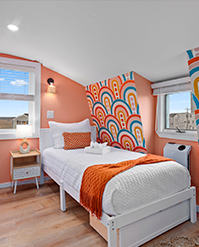 Attic bedroom with a rainbow arch mural and coral walls