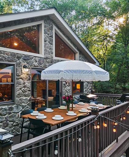 Stone lodge with a deck dining table under a striped parasol