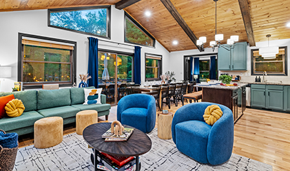 Open-plan lounge with blue armchairs under a timber vaulted ceiling