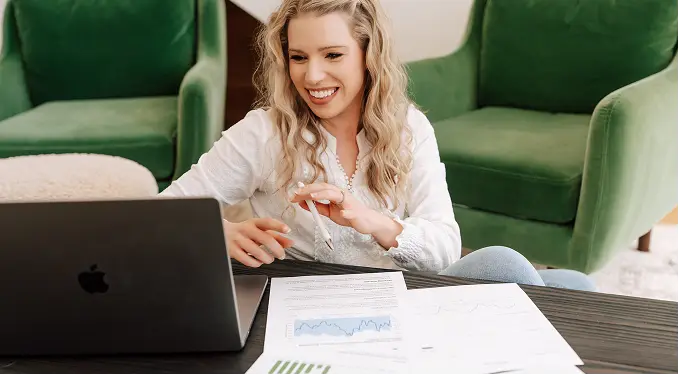 Designer working at a laptop beside a green velvet sofa