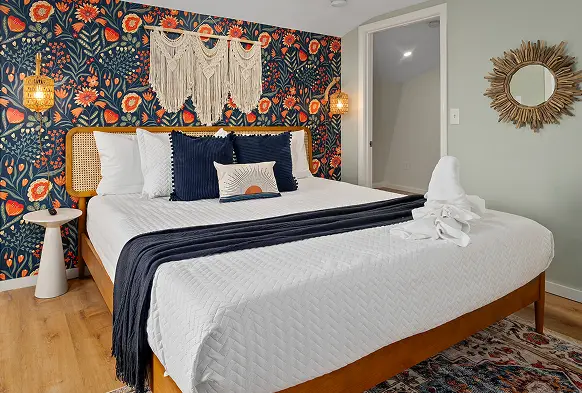 Bedroom with a folk-floral headboard wall and navy bedding