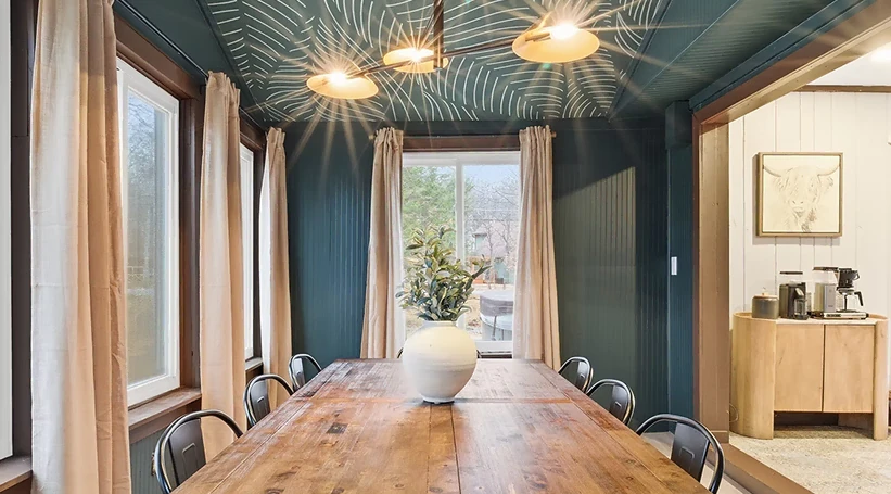 Dining room with a patterned teal ceiling and timber table