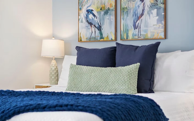 Bed with heron prints, navy cushions and a sage throw