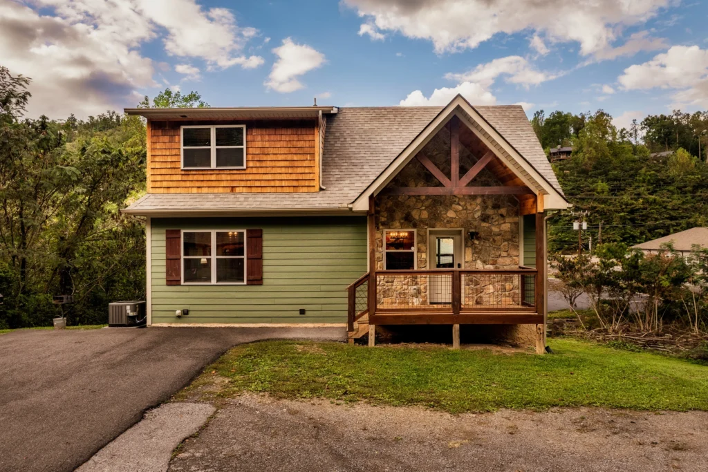 Timber and green clapboard cabin seen from the driveway