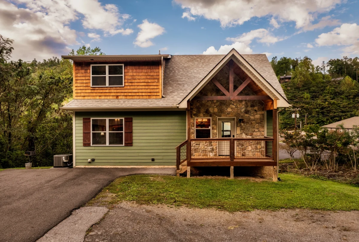 Timber and green clapboard cabin seen from the driveway