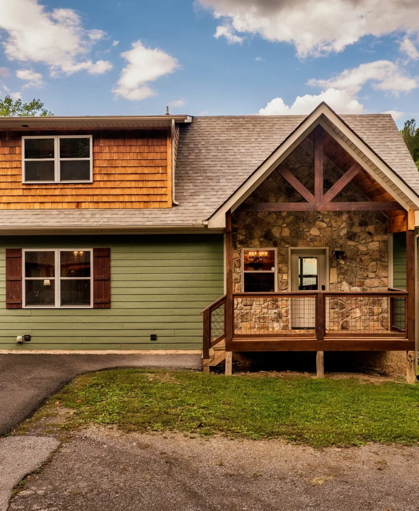 Timber and green clapboard cabin seen from the driveway