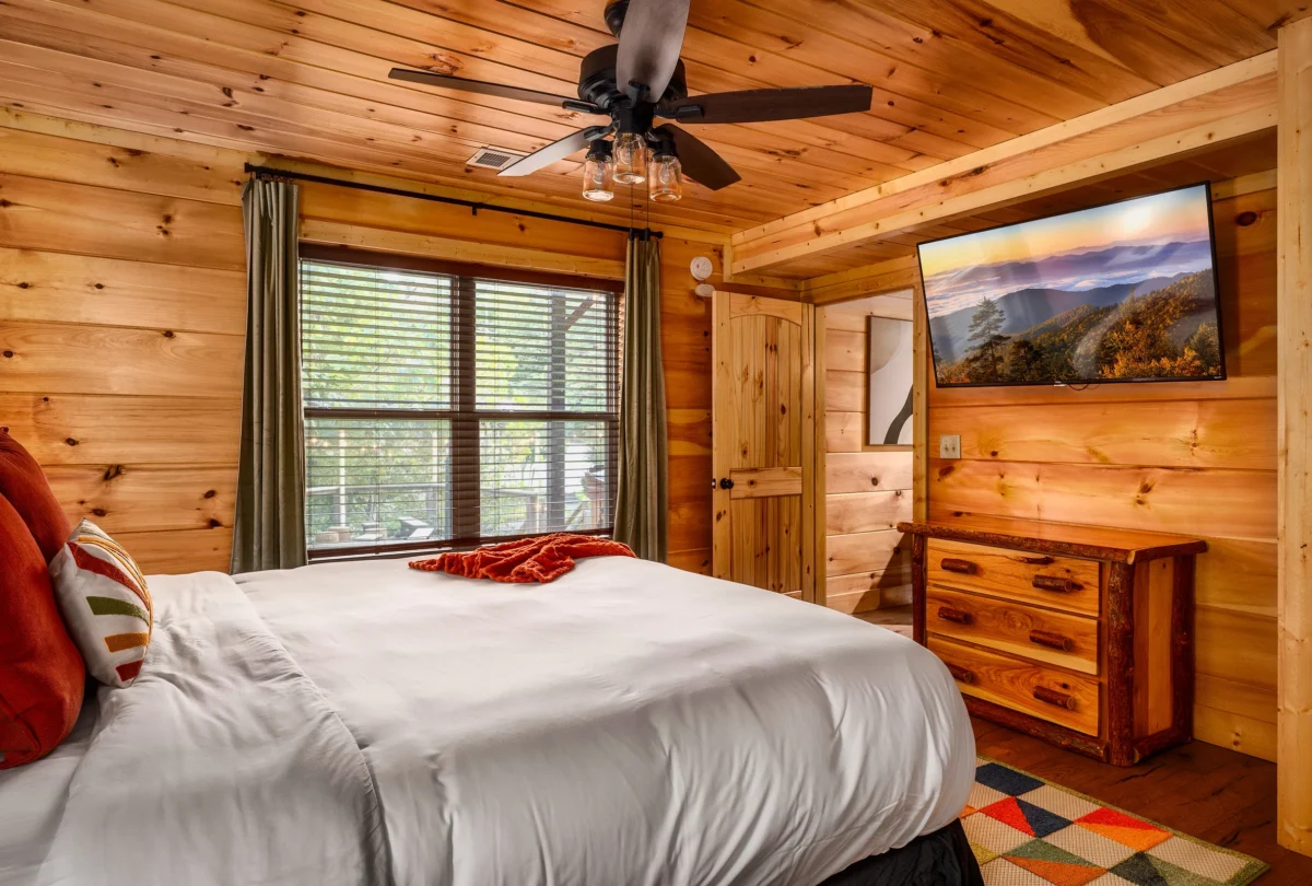 Bedroom with pine walls and a rust throw across the bed