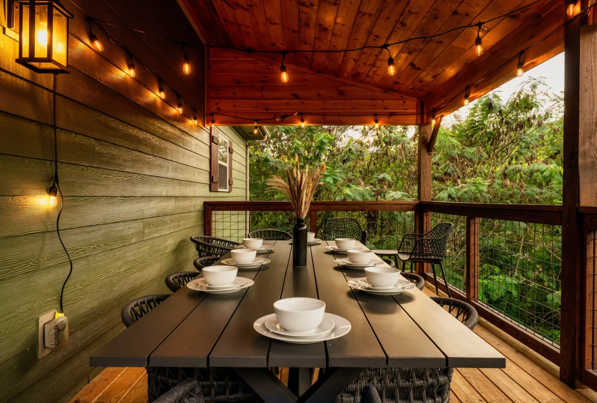 Covered deck dining table at dusk under string lights