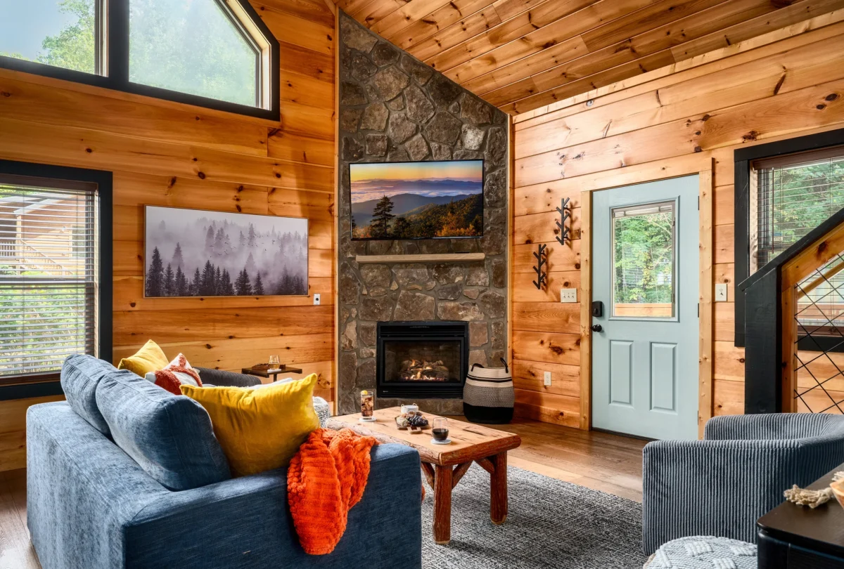 Living room with a stone fireplace and blue sofas under pine walls