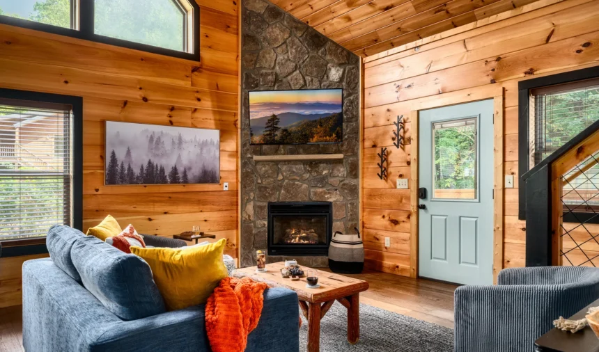 Living room with a stone fireplace and blue sofas under pine walls