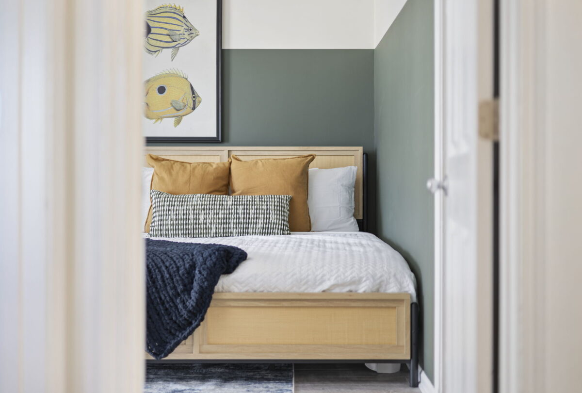 Bedroom corner with tropical fish prints above a pale wood bed