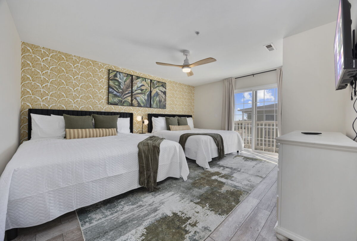 Bedroom with two beds, palm-leaf artwork and a balcony door