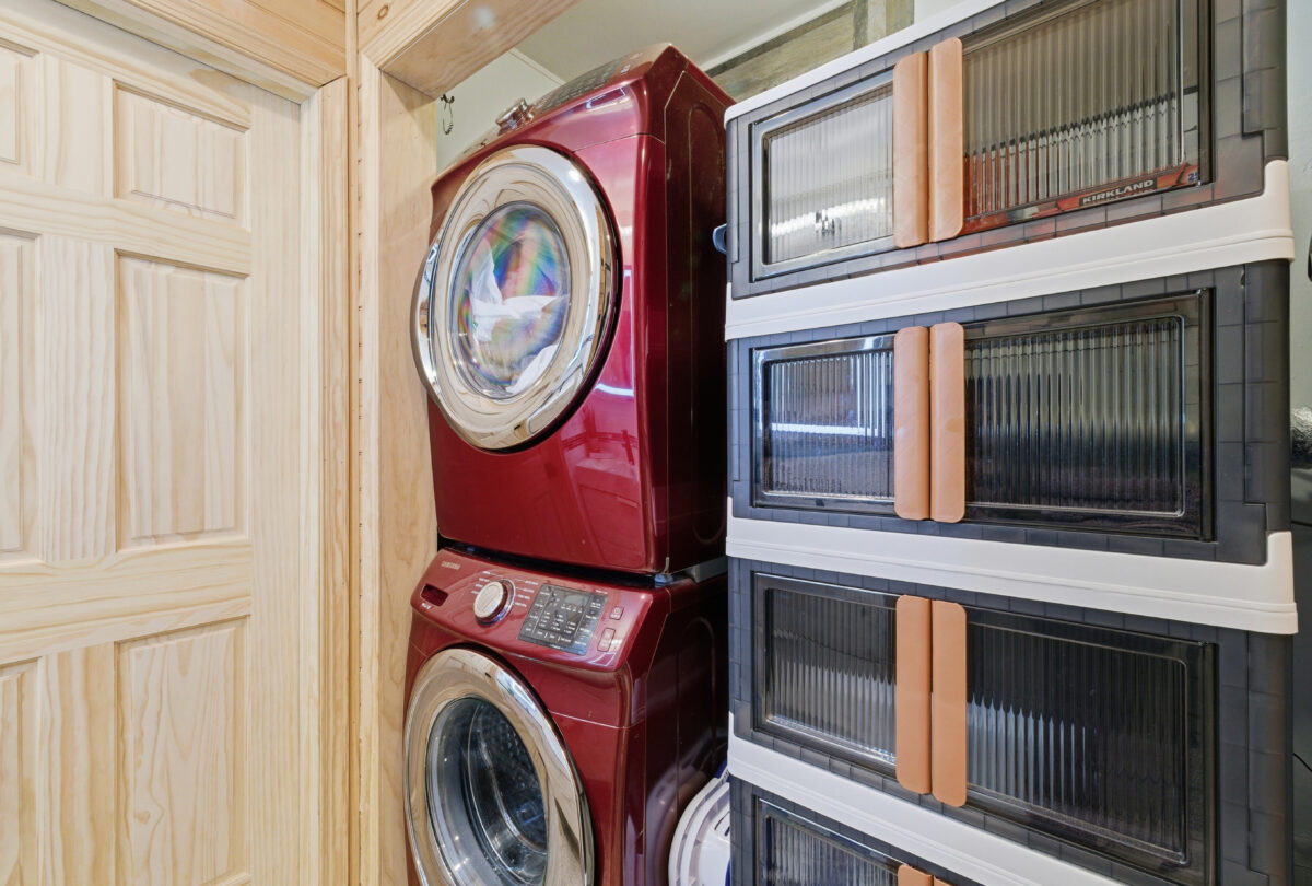 Laundry nook with a red stacked washer and dryer beside fluted glass cabinets
