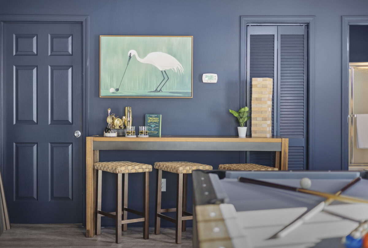 Navy games room with a heron print, rattan bar stools and a pool table