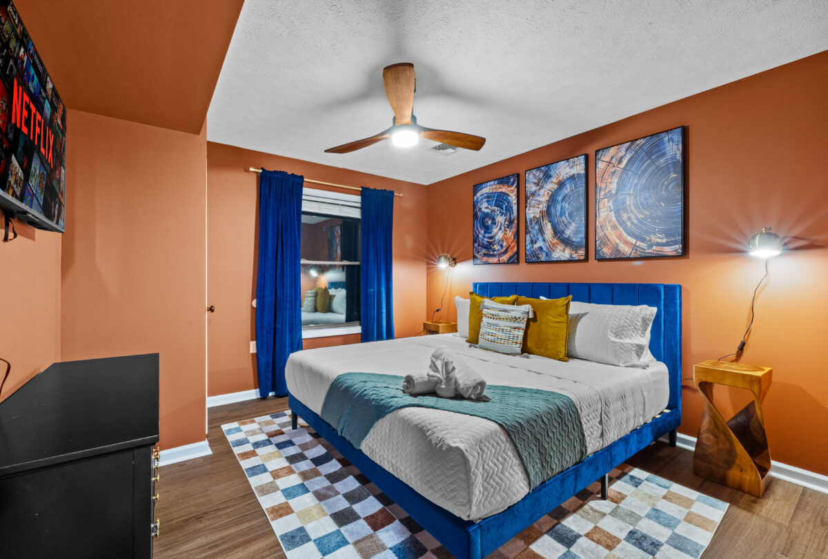 Bedroom with terracotta walls, a blue velvet bed and abstract prints