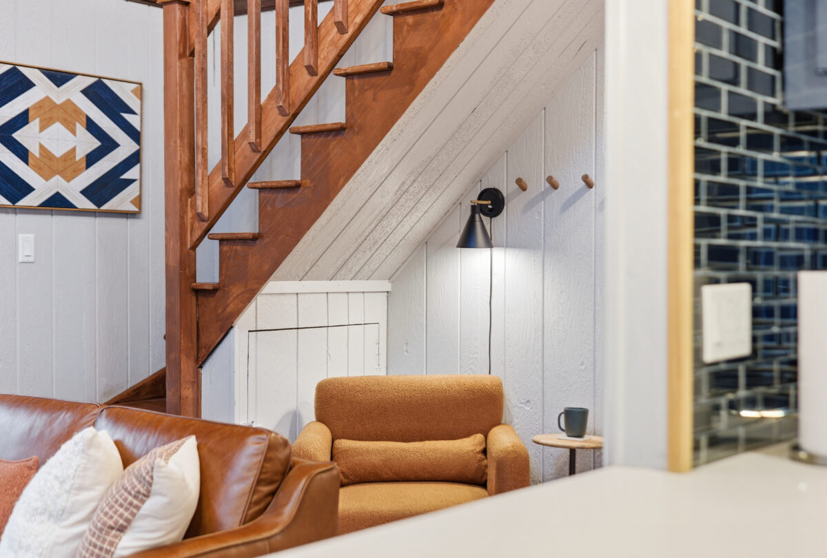 Reading nook with a leather armchair tucked beneath a timber staircase