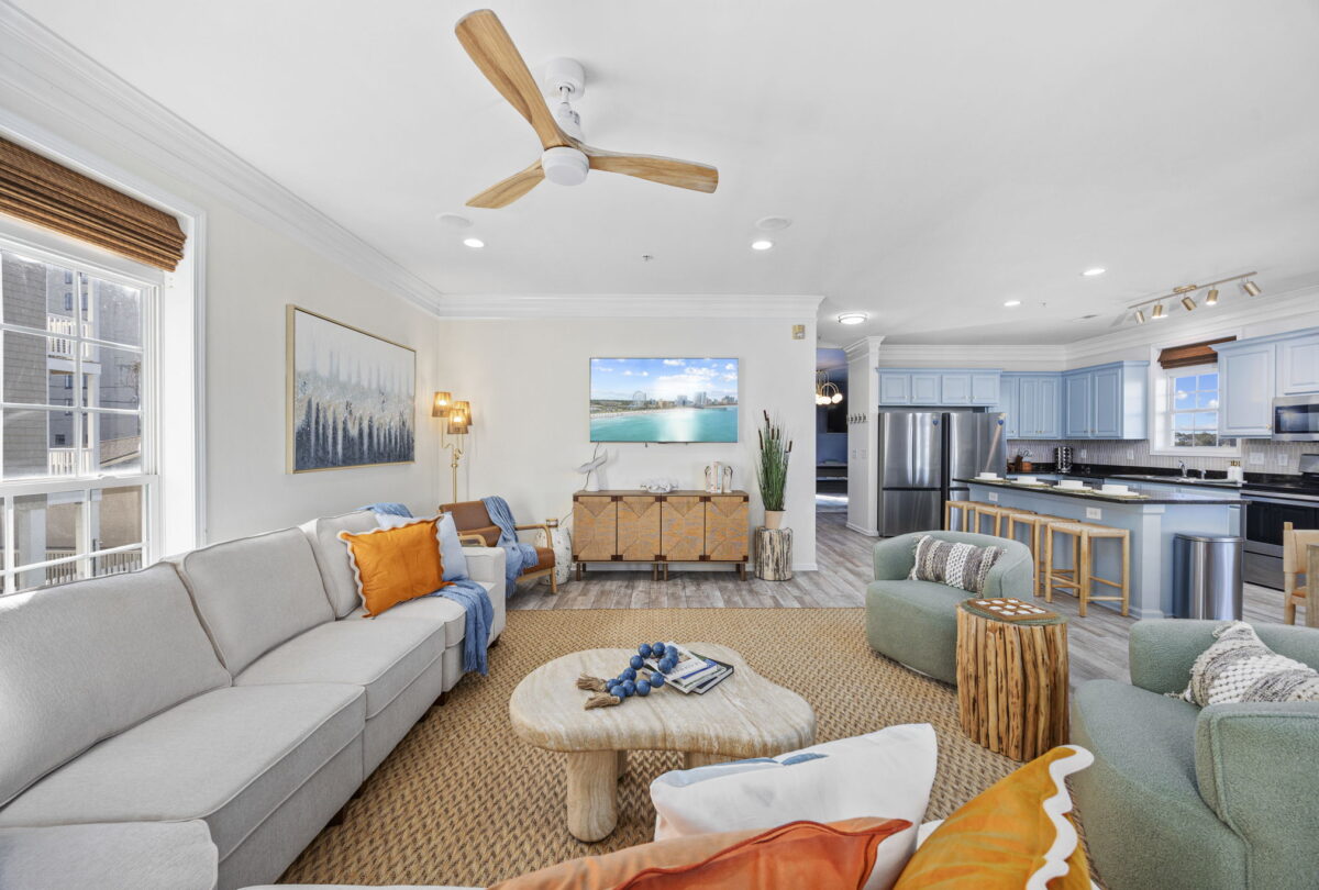 Open-plan living room with a cream sectional and a view through to the kitchen