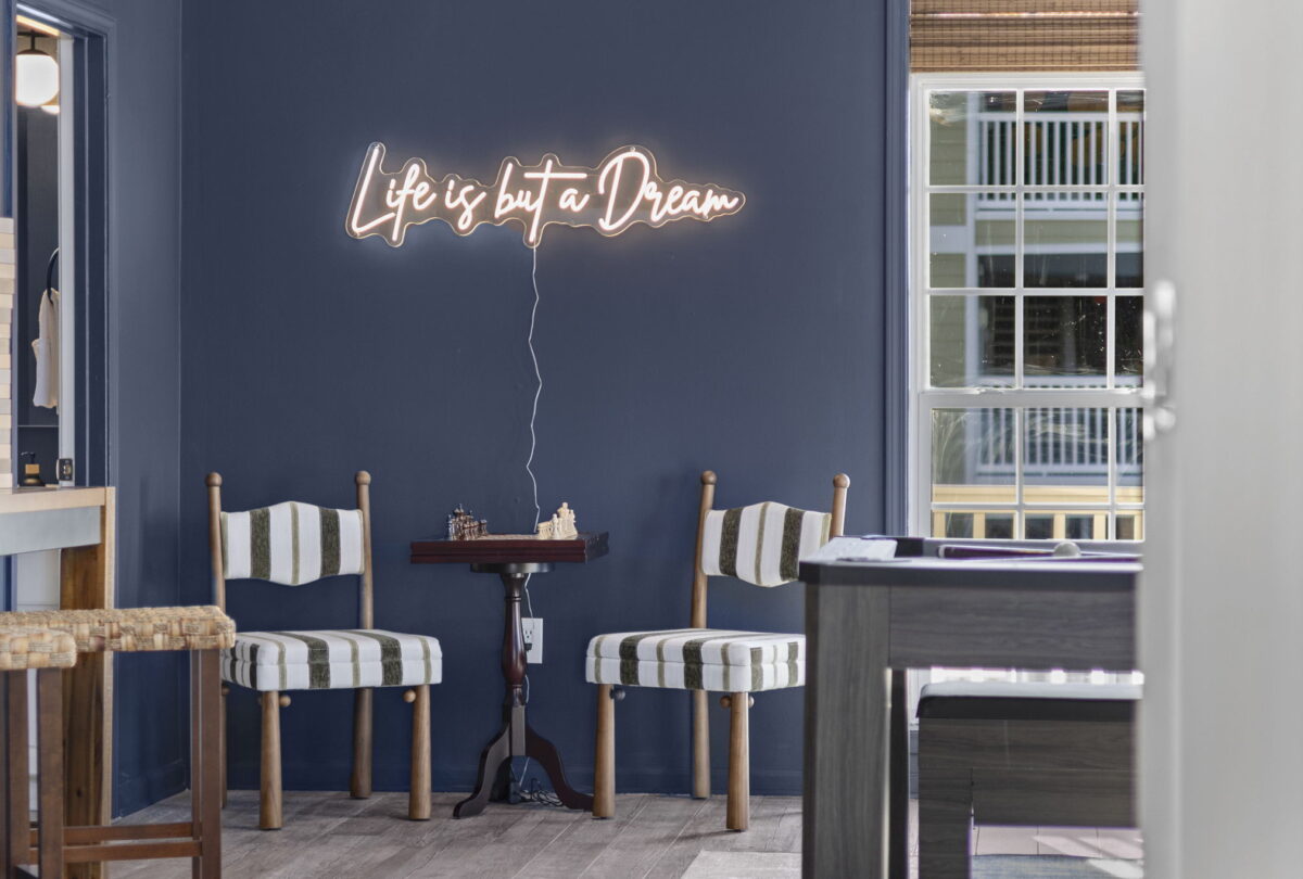 Navy bar area with a neon Life is but a Dream sign and striped stools