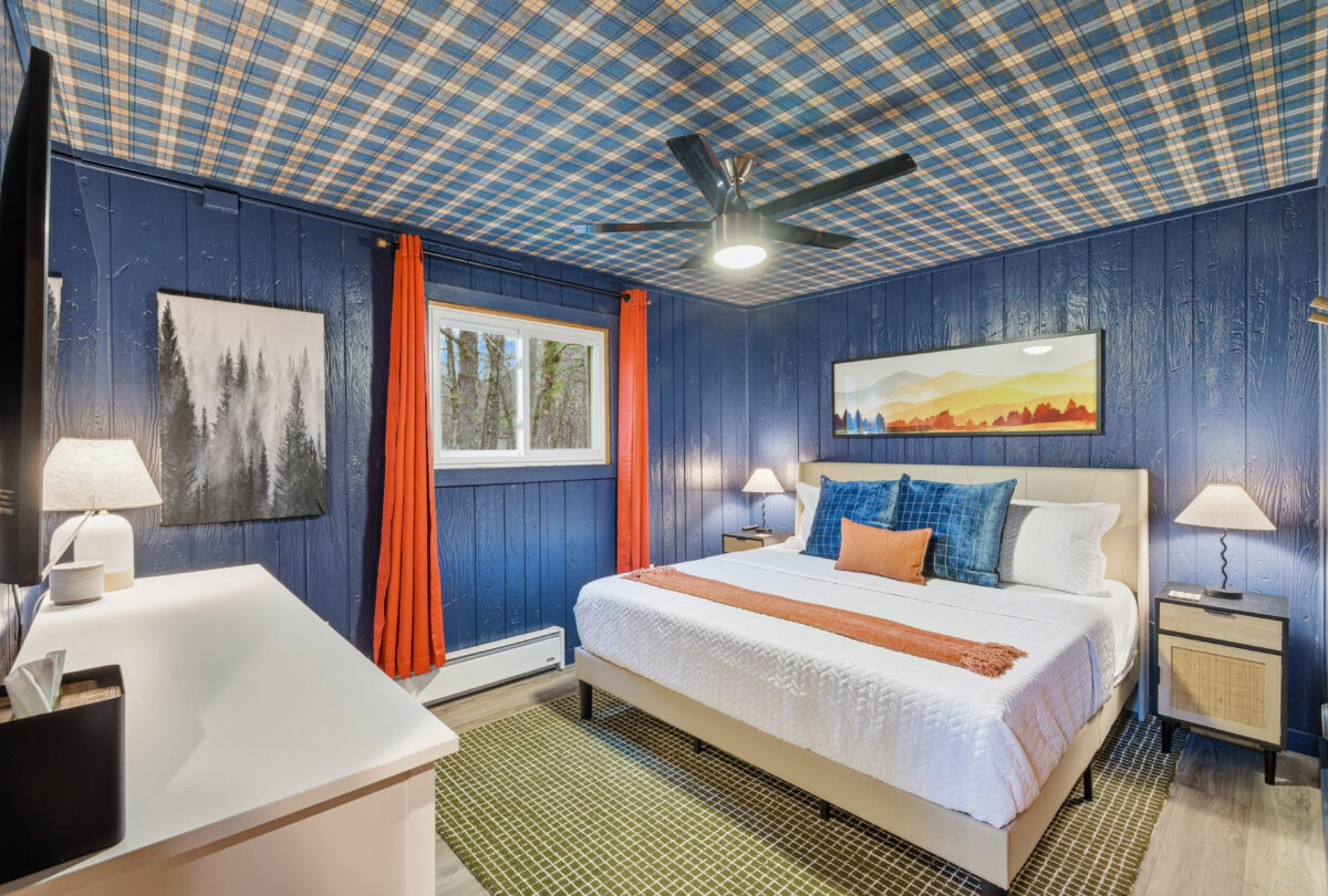 Bedroom with navy panelling, a plaid ceiling and orange curtains