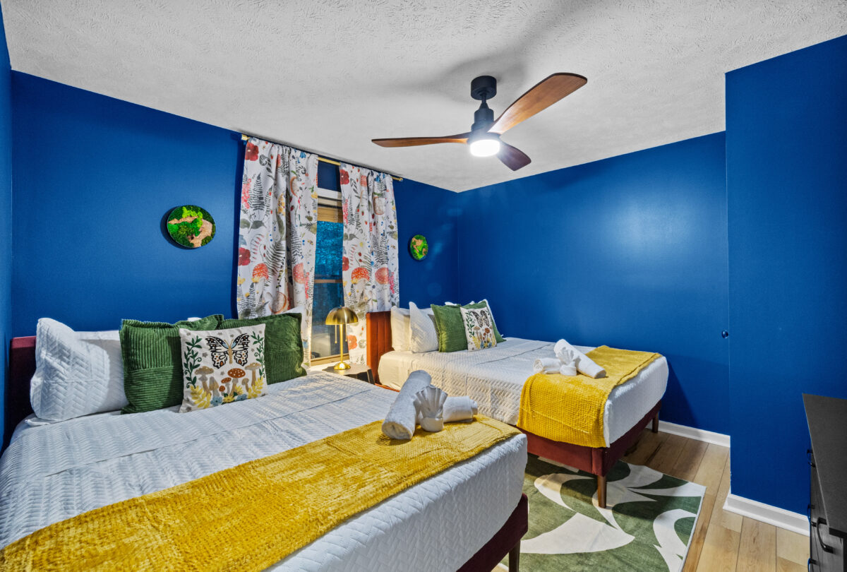 Bedroom with cobalt walls, yellow bedding and a floral curtain
